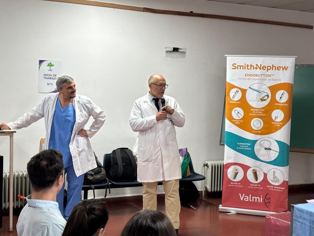 Instructor junto a colega presentando el taller, con cartel de Mesa de Trabajo N°3 y panel de la firma auspiciante