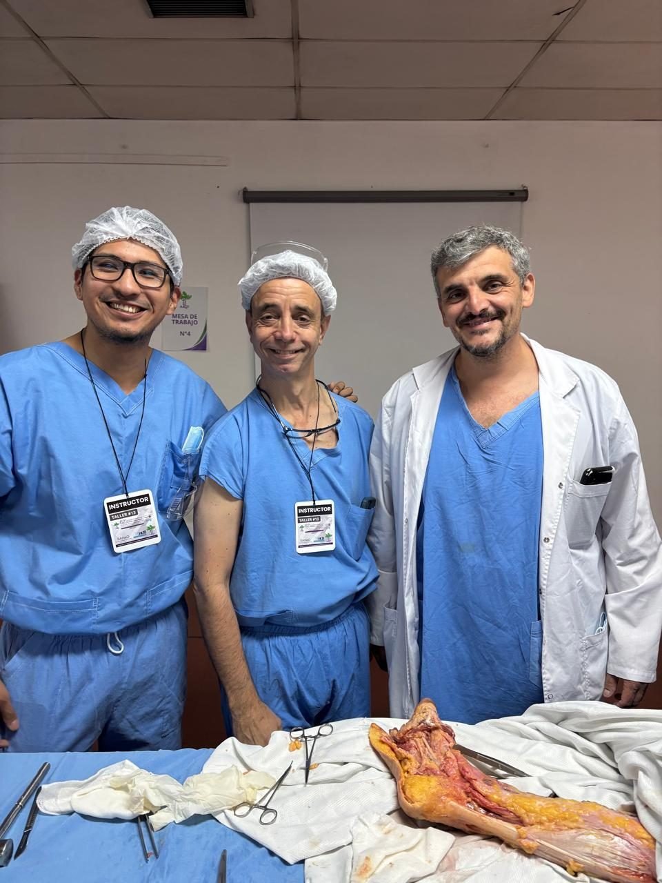 Tres instructores del Taller N°12 junto a una pieza anatómica de pie utilizada en la práctica
